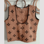 Sleeveless beige top with black star patterns and front buttons.