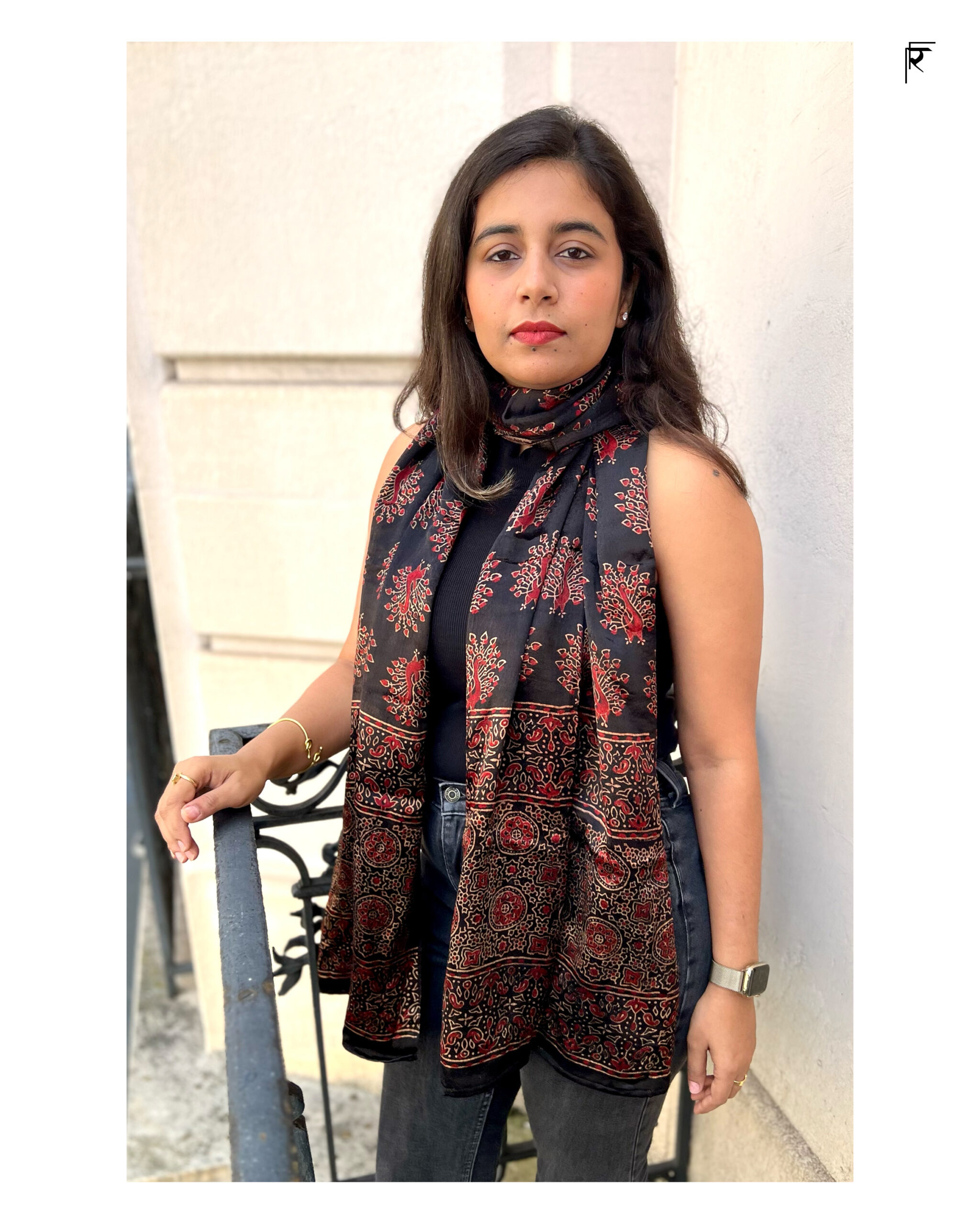 Woman posing indoors wearing a sleeveless patterned top and scarf.