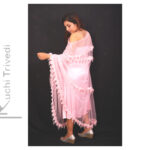 Woman in a soft pink traditional dress with delicate tassel detailing.