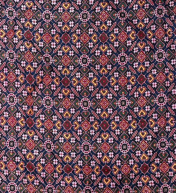 Detailed geometric pattern in warm colors on dark fabric.